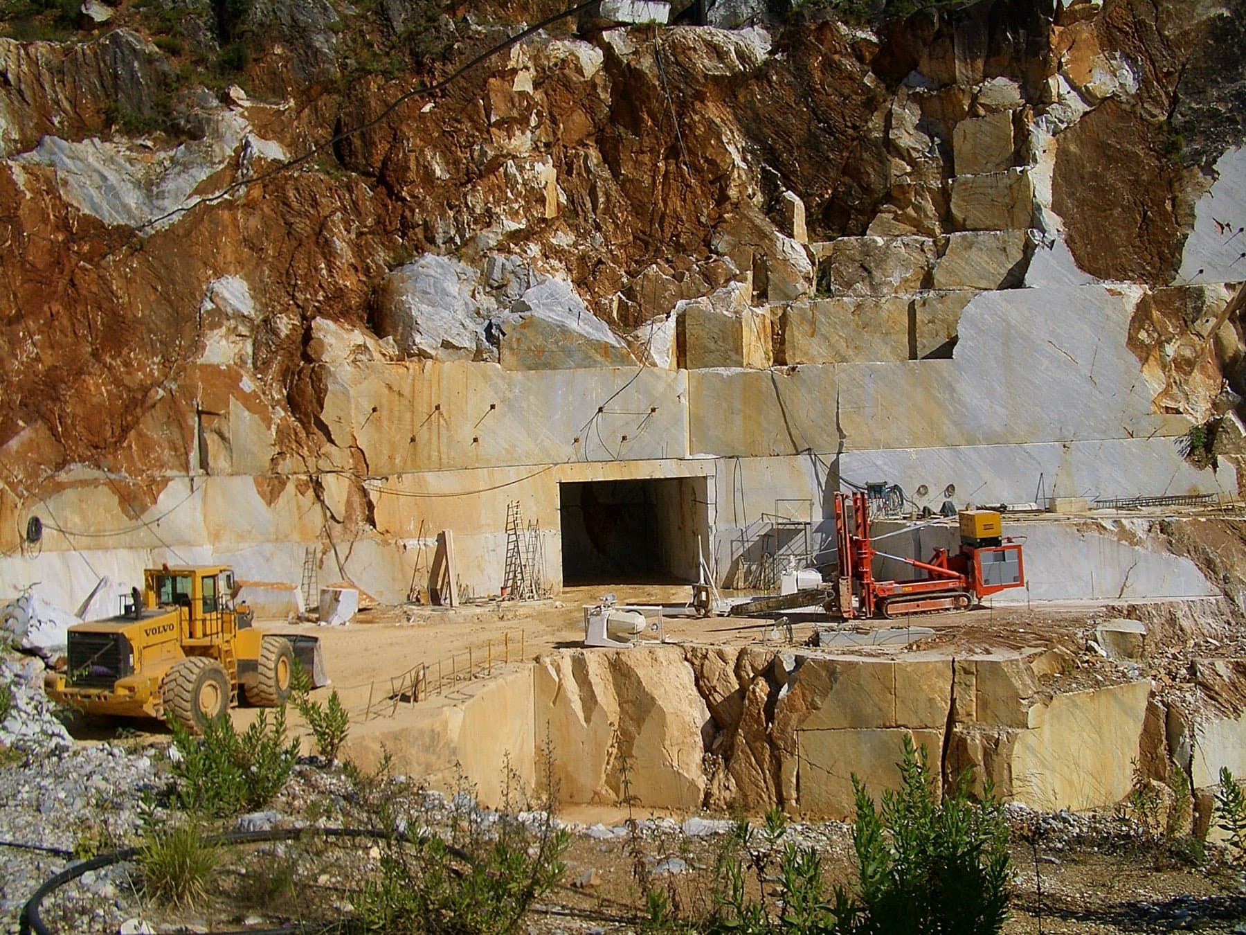 A marble quarry face worked in benches with a loader at the floor.
