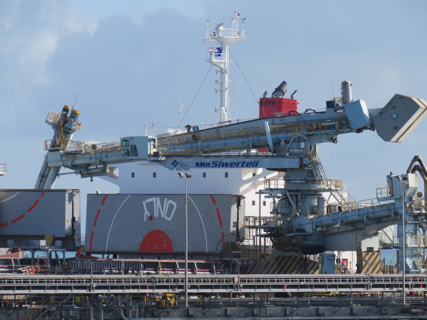 A ship unloader working over the hold of a bulk carrier at a jetty.