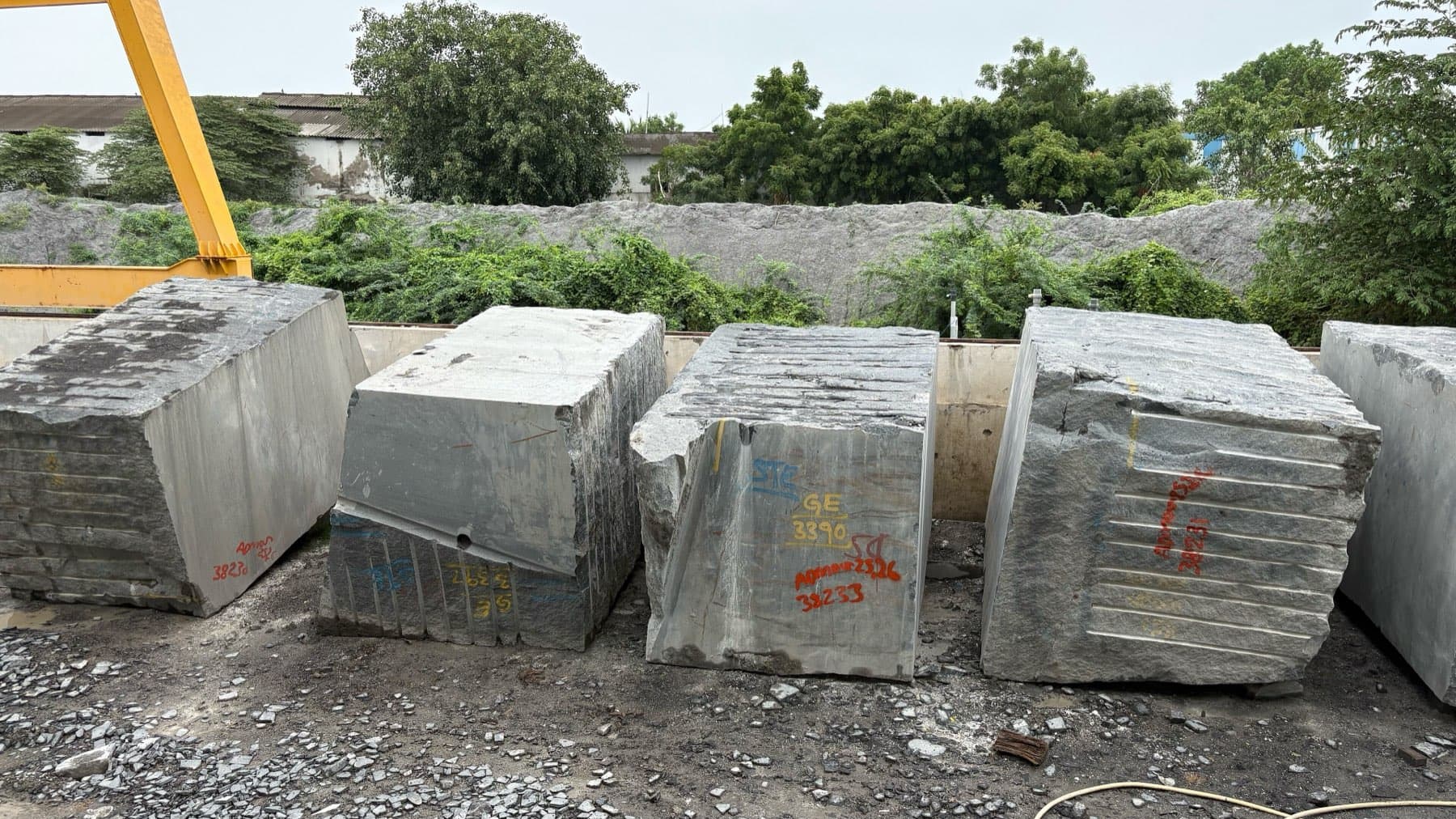 Squared granite blocks chalk marked and set out in a processing yard.