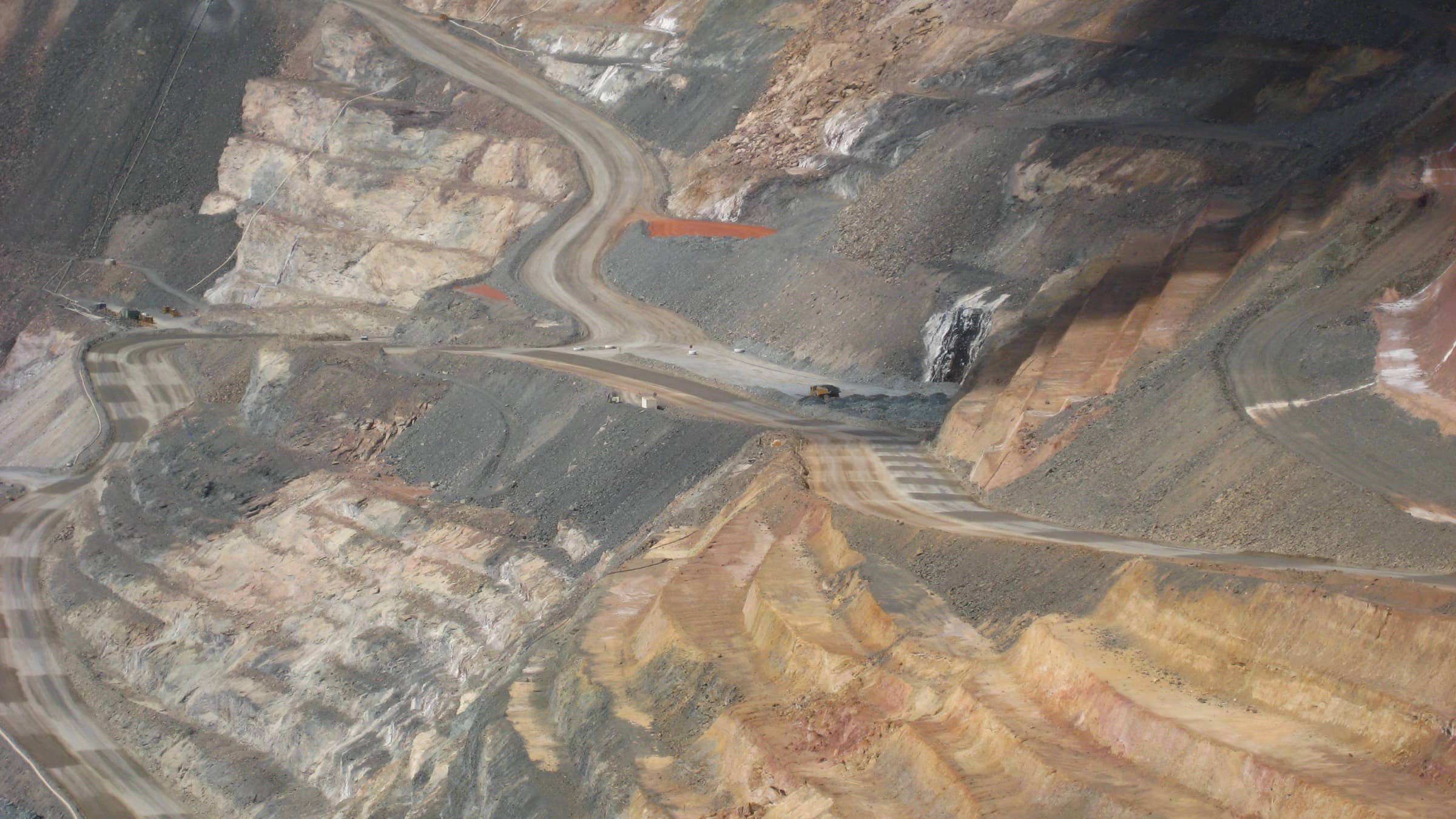 An open pit worked in benches, haul roads switchbacking down the mineralised wall to the working floor