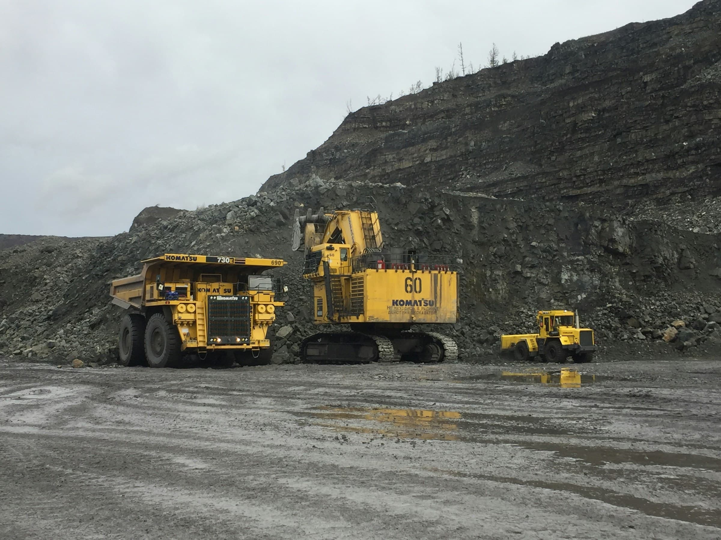 A haul truck and a hydraulic excavator standing on the floor of a working mine